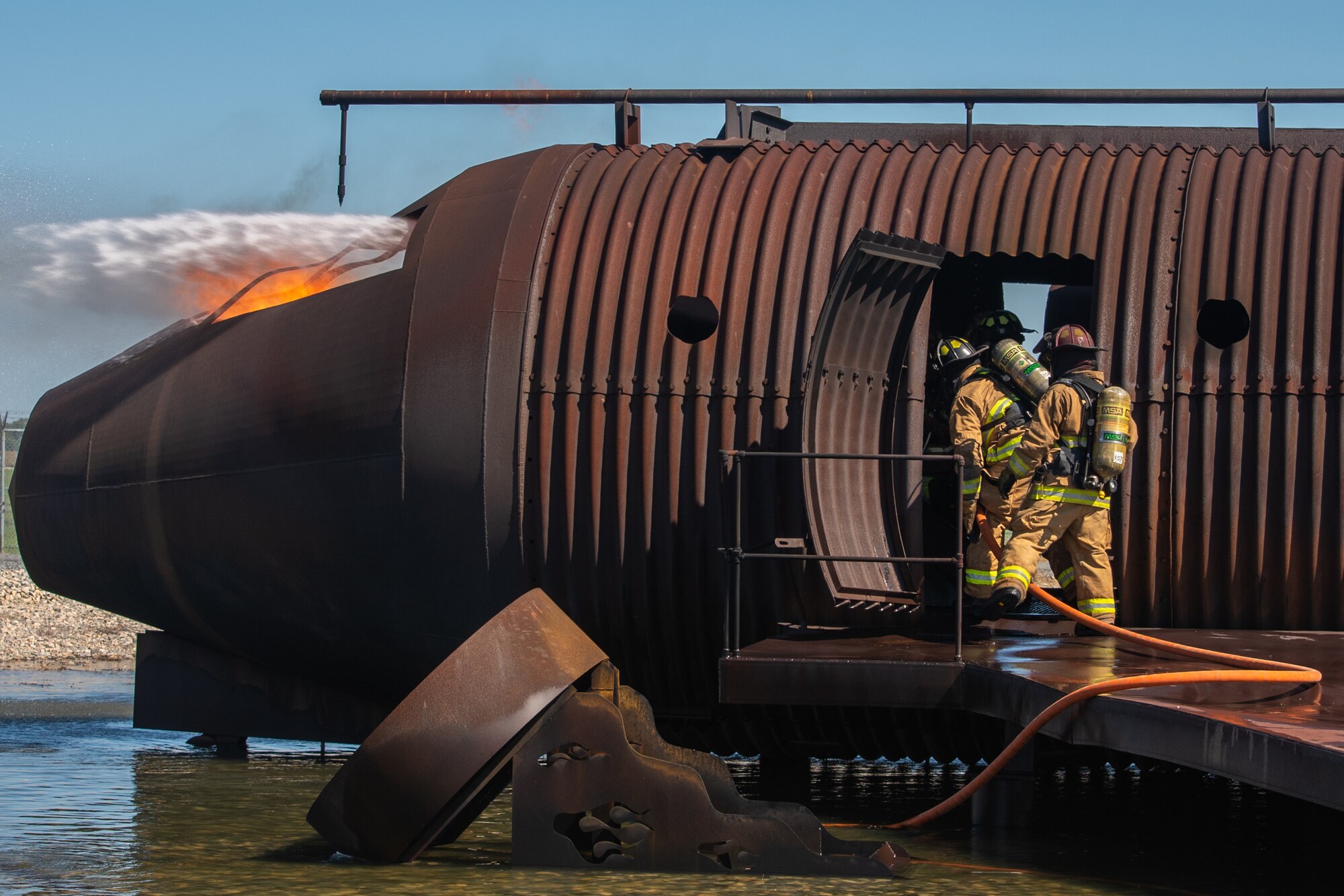Firefighters from the 436th Civil Engineer Squadron and 177th Fighter Wing extinguish flames inside an aircraft fire trainer at the aircraft-live-fire training structure, Sept. 22, 2020, Dover Air Force Base, Delaware. Aircraft-live-fire training sessions are used to refresh proficiencies and satisfy other annual training requirements firefighters are required to complete. (U.S. Air Force photo by Airman Brandan Hollis)