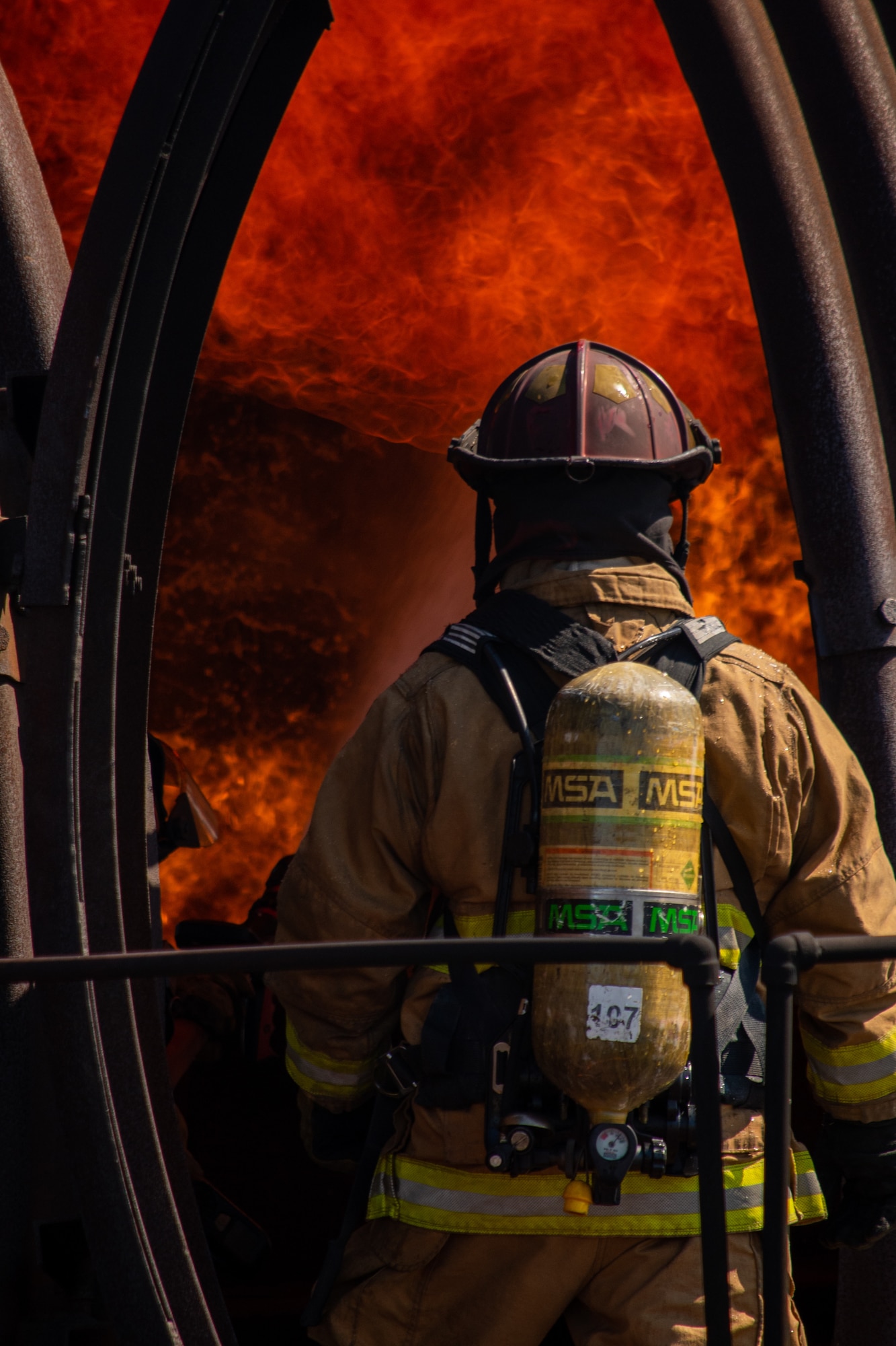 A U.S. Air Force firefighter enters an aircraft fire trainer during an exercise at Dover Air Force Base, Delaware, Sept. 22, 2020. Temperatures inside the aircraft fire trainer can reach up to 1,500 degrees Fahrenheit. (U.S. Air Force photo by Airman Brandan Hollis)