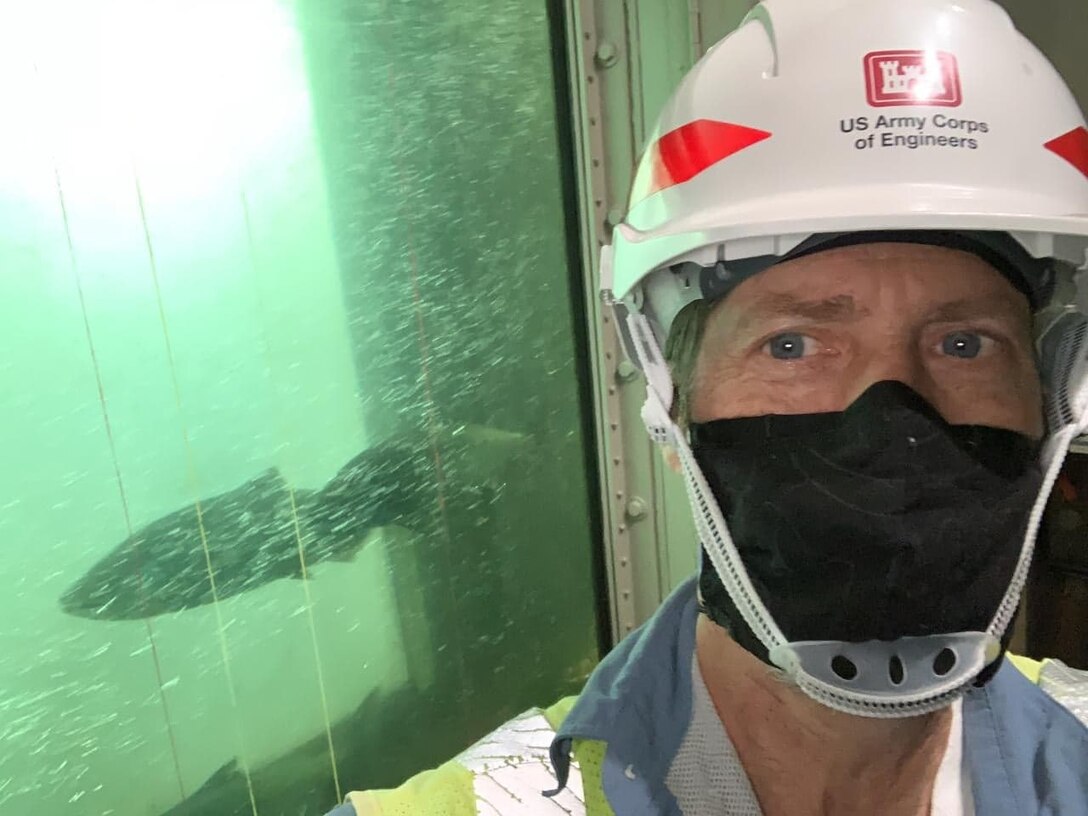 Jim Day, fisheries biological technician at The Dalles Lock and Dam, snaps a selfie in front of the East fish counting station window. Fish are counted as they swim through the fish ladders at the dam.