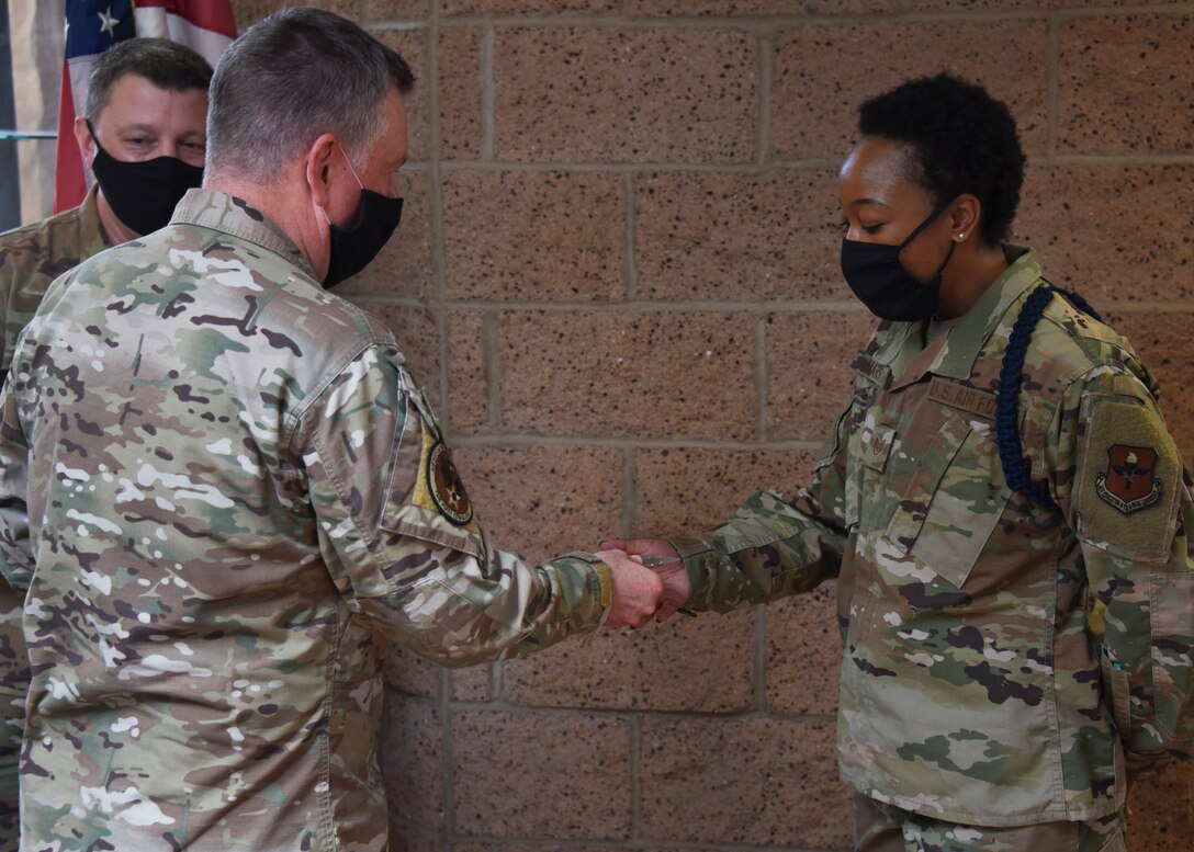 Lt. Gen. Brad Webb, commander of Air Education and Training Command, coins Staff Sgt. Javone Mars