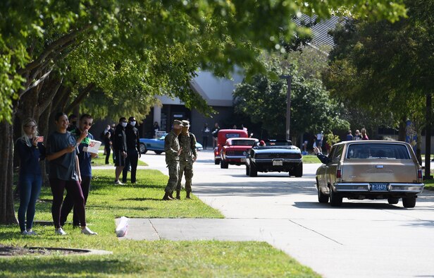 Airmen watch classic vehicles drive by on the triangle troop walk during the 17th Annual Cruisin' Keesler Car Show - Parade Edition at Keesler Air Force Base, Mississippi, Oct. 3, 2020. The event is held to kick off Cruisin' the Coast, a festival to celebrate classic cars, trucks and hot rods, where vehicles cruise down the 30-mile beachside highway in Mississippi. (U.S. Air Force photo by Kemberly Groue)