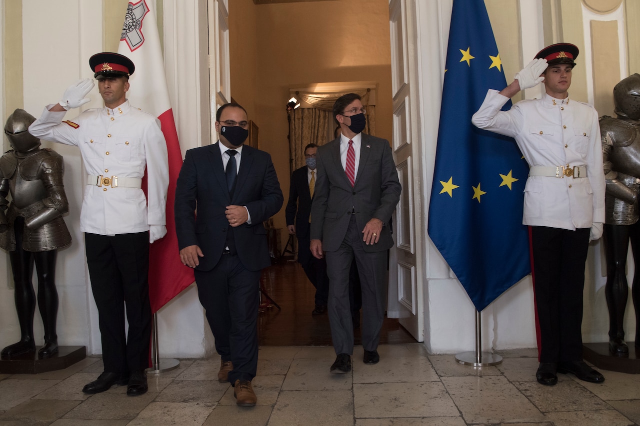 Two Maltese soldiers salute as men leave room.