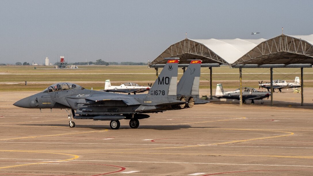 An F-15E Strike Eagle from the 389th Fighter Squadron taxis for takeoff at Vance AFB while student pilots start and taxi in the T-6 Texan II pilot trainer. (U.S. Air Force photo by Maj. Mark Calendine)