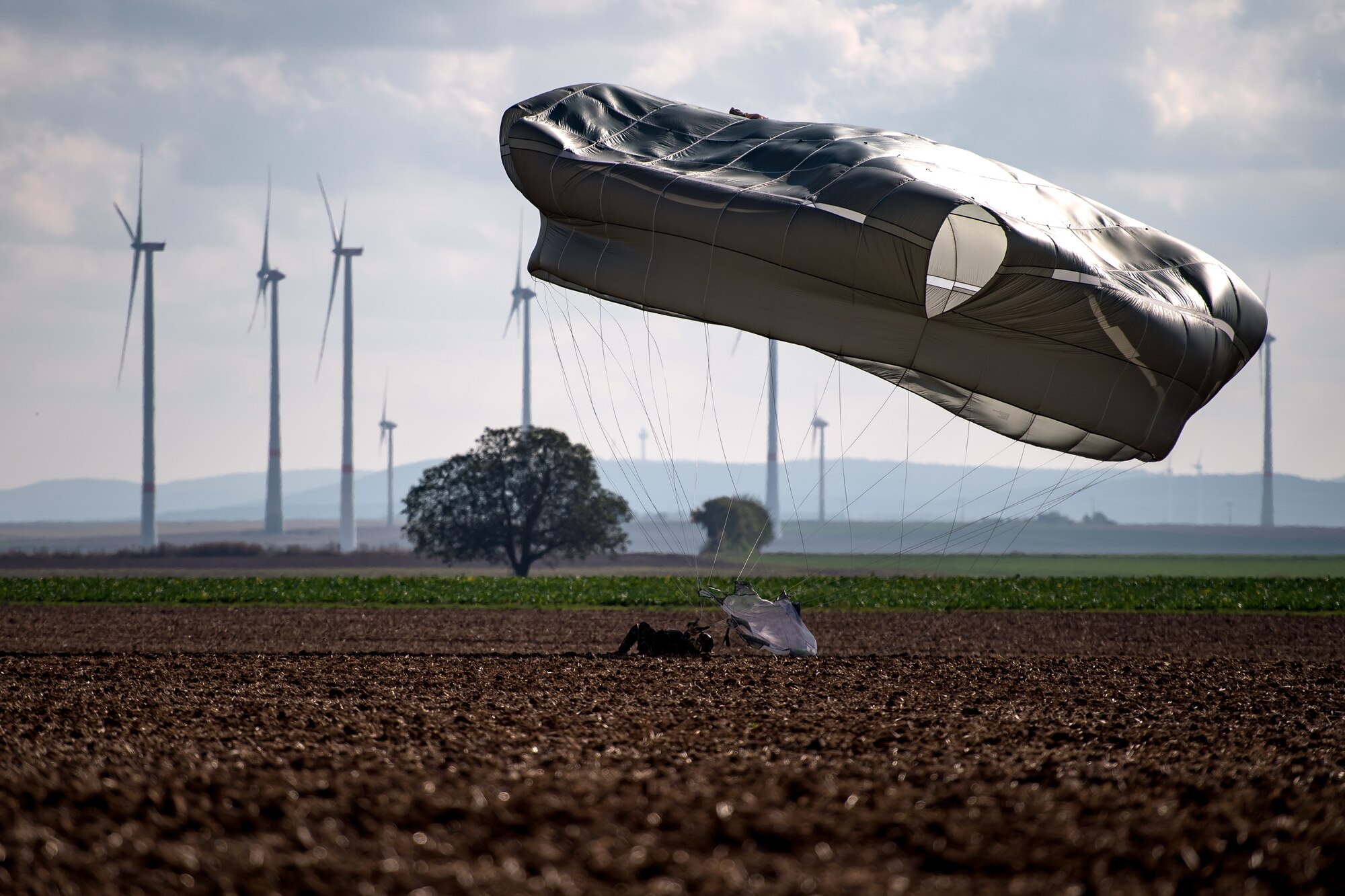Photo of Airman landing on dirt after parachuting