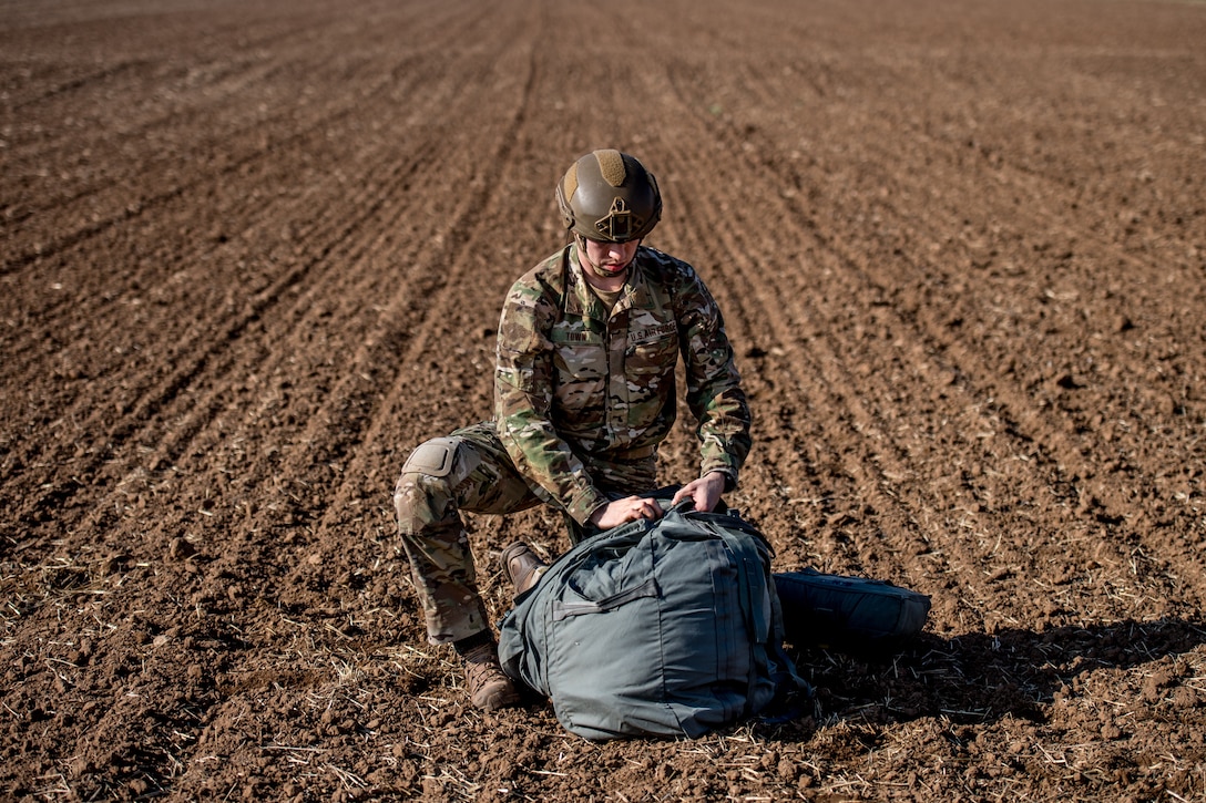 Photo of Airman stuffing a parachute into a bag