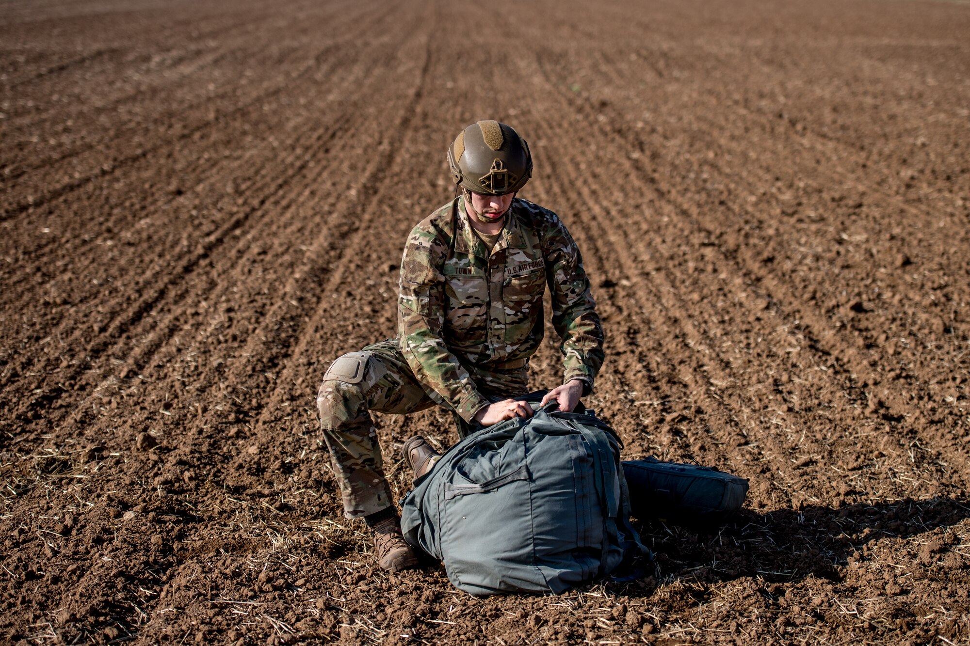 Photo of Airman stuffing a parachute into a bag