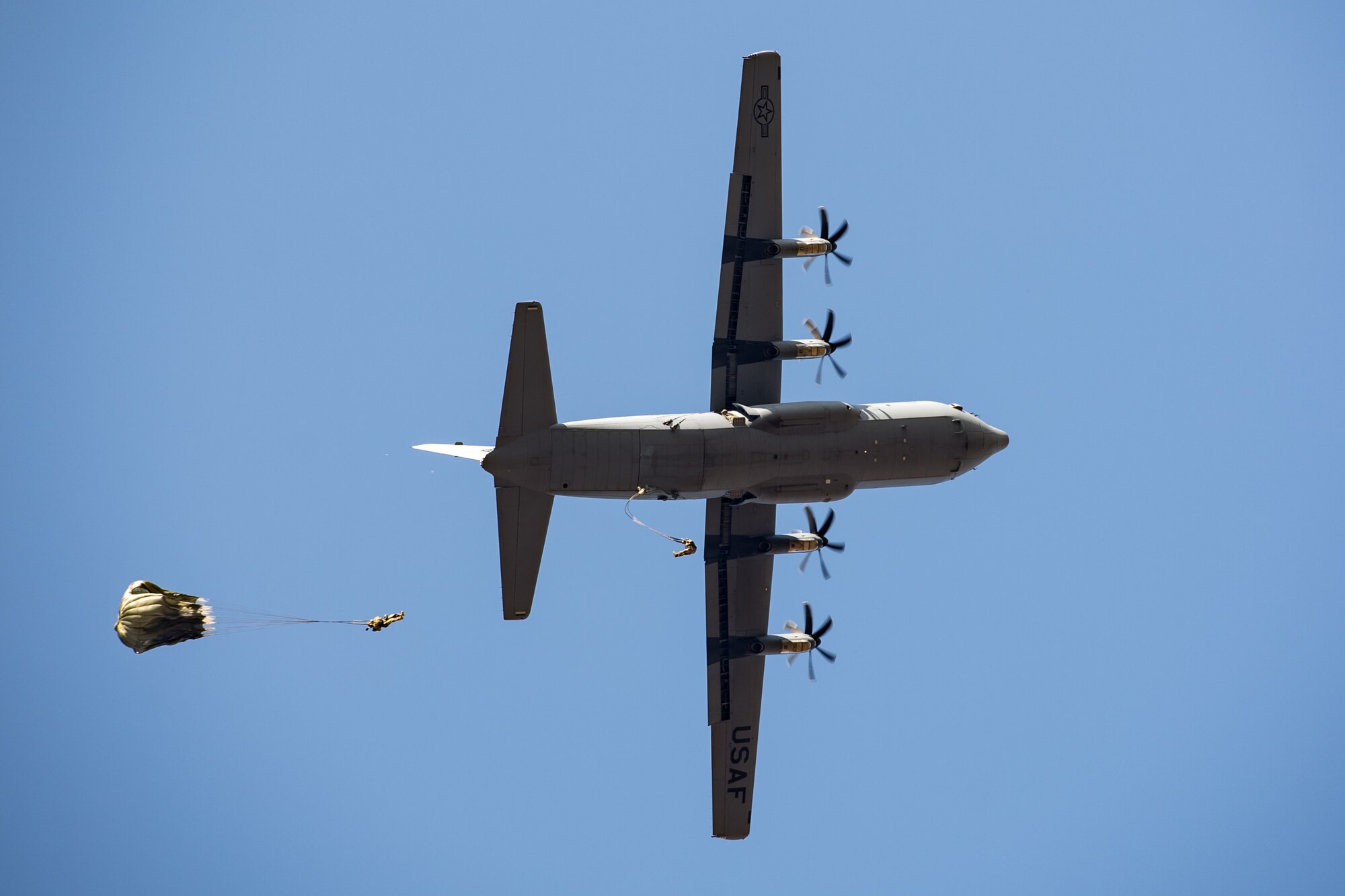 Photo of Airmen jumping out of an aircraft with parachutes