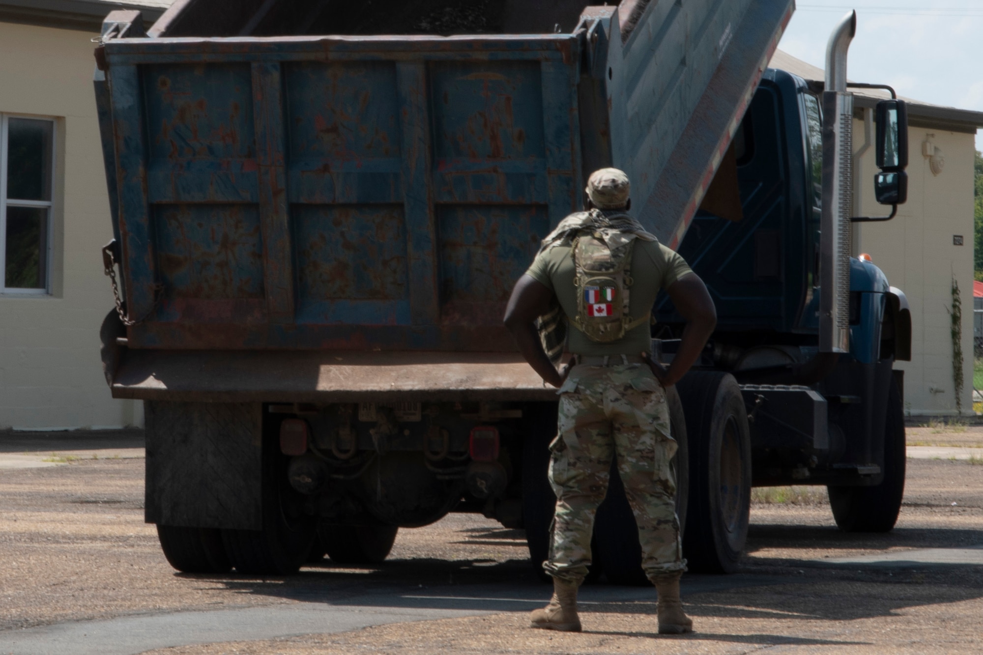 Photo of Airman standing behind a dump truck.