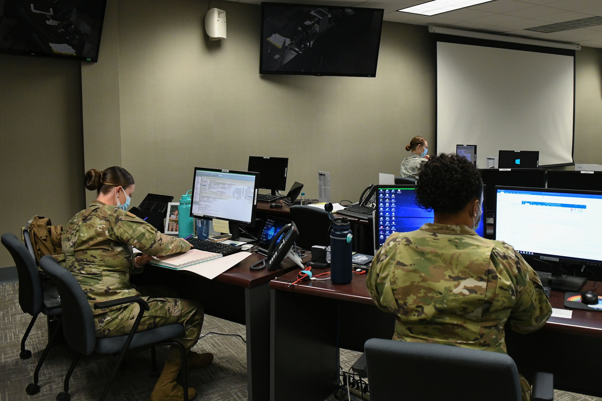two women sitting in a room surrounded by computers collecting COVID-19 data