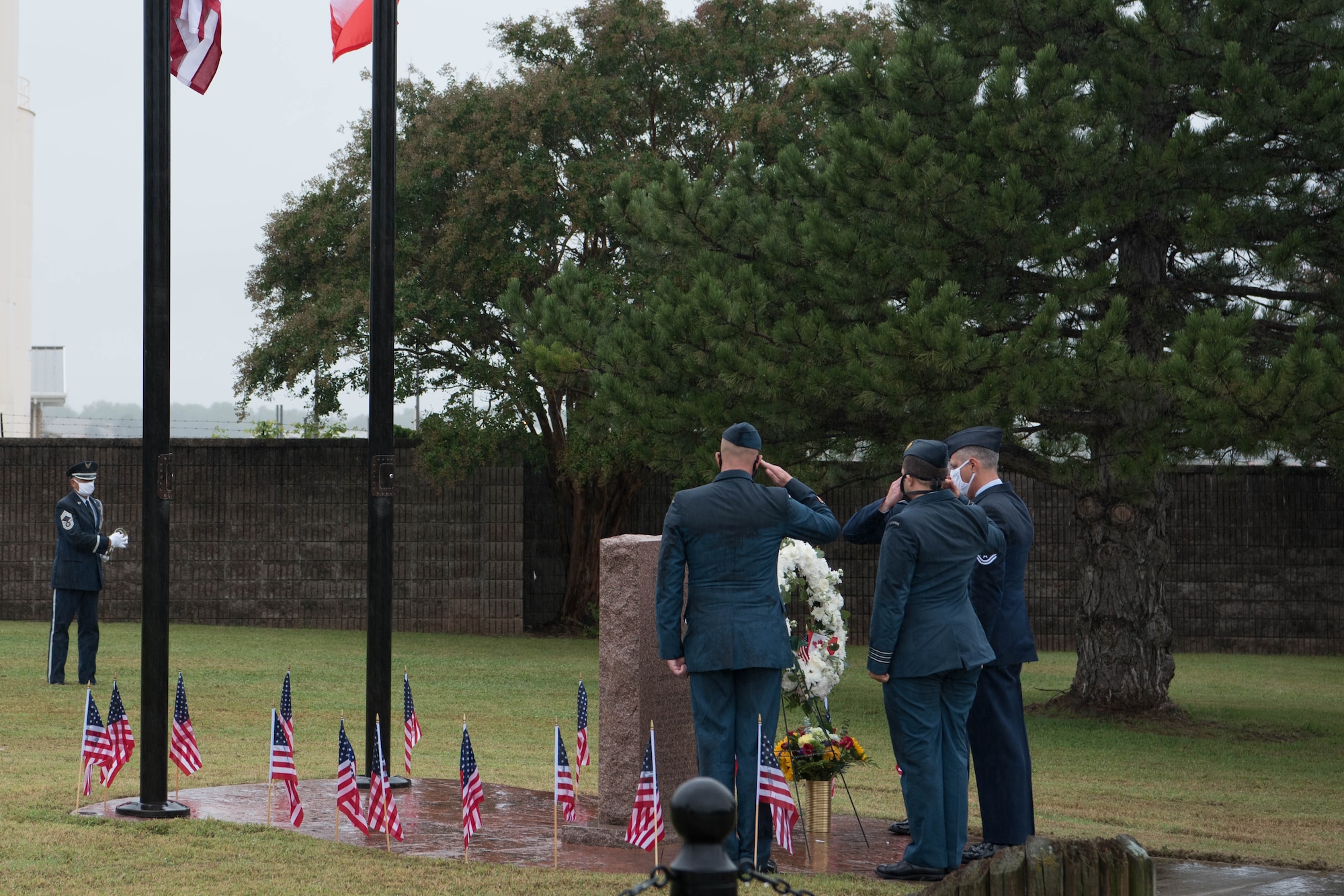 Three men saluting, facing wreath of flowers