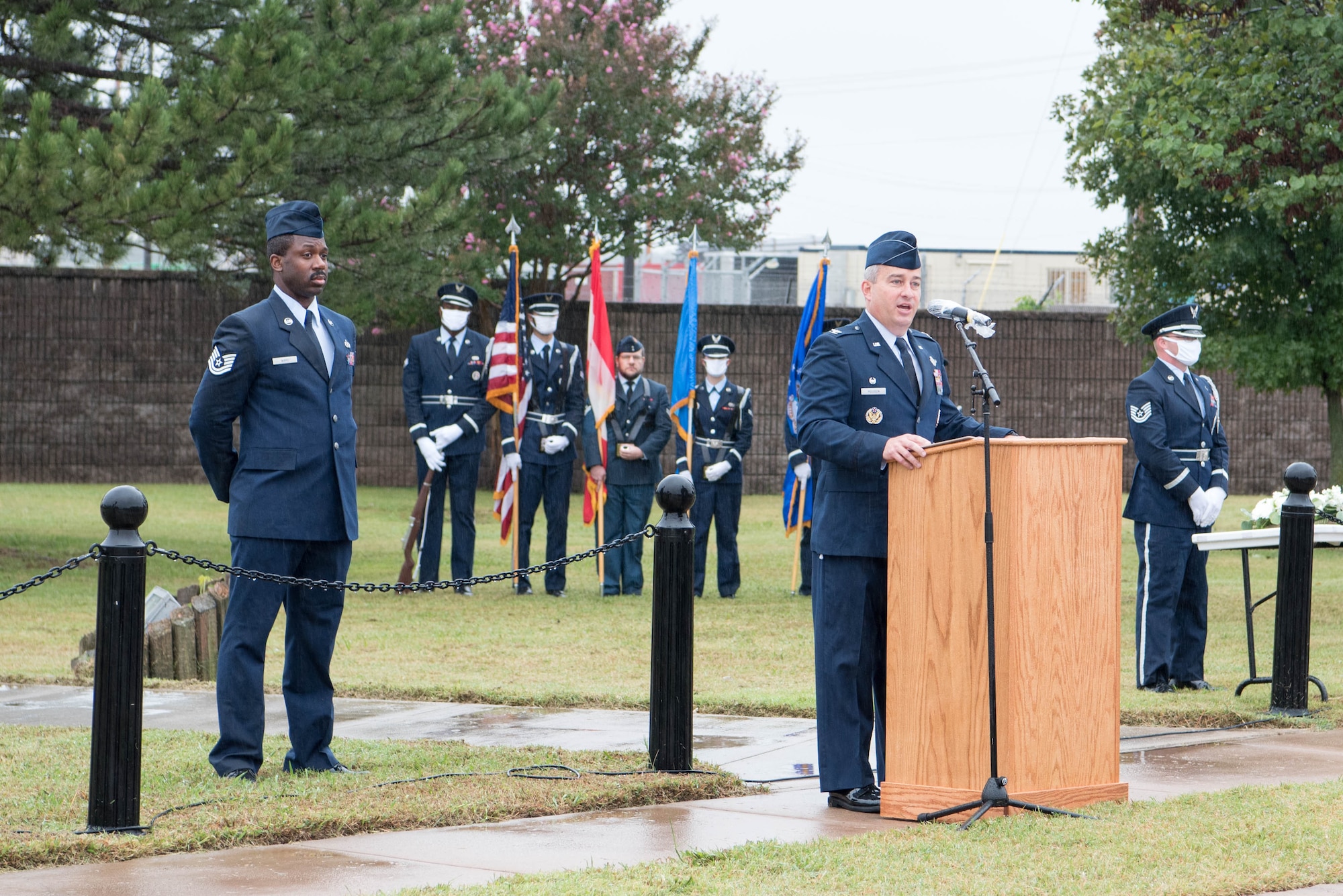 Man standing at podium with honor guard behind him.