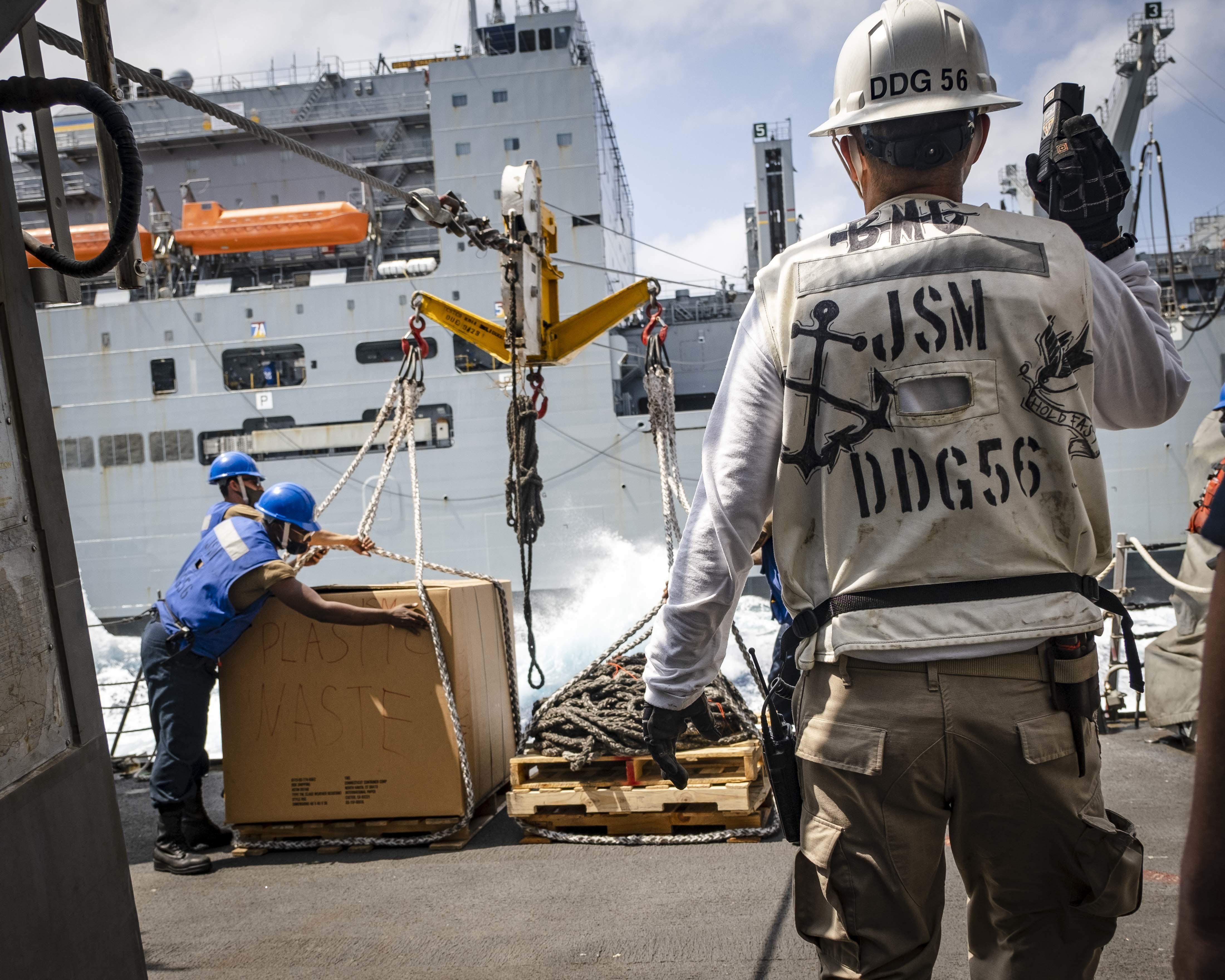 A Sailor observes as riggers prepare to send a pallet from USS John S. McCain (DDG 56) to the Lewis and Clark-class dry cargo and ammunition ship USNS Charles Drew (T-AKE 10) during a replenishment-at-sea.