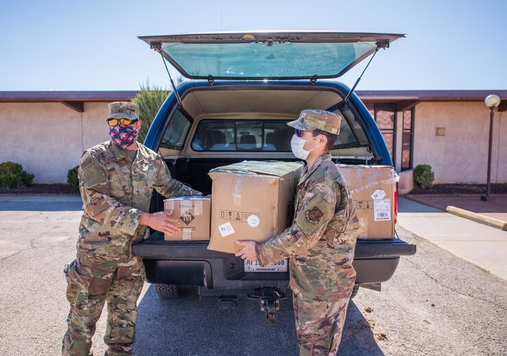 Two Airmen in uniform delivering supplies during COVID
