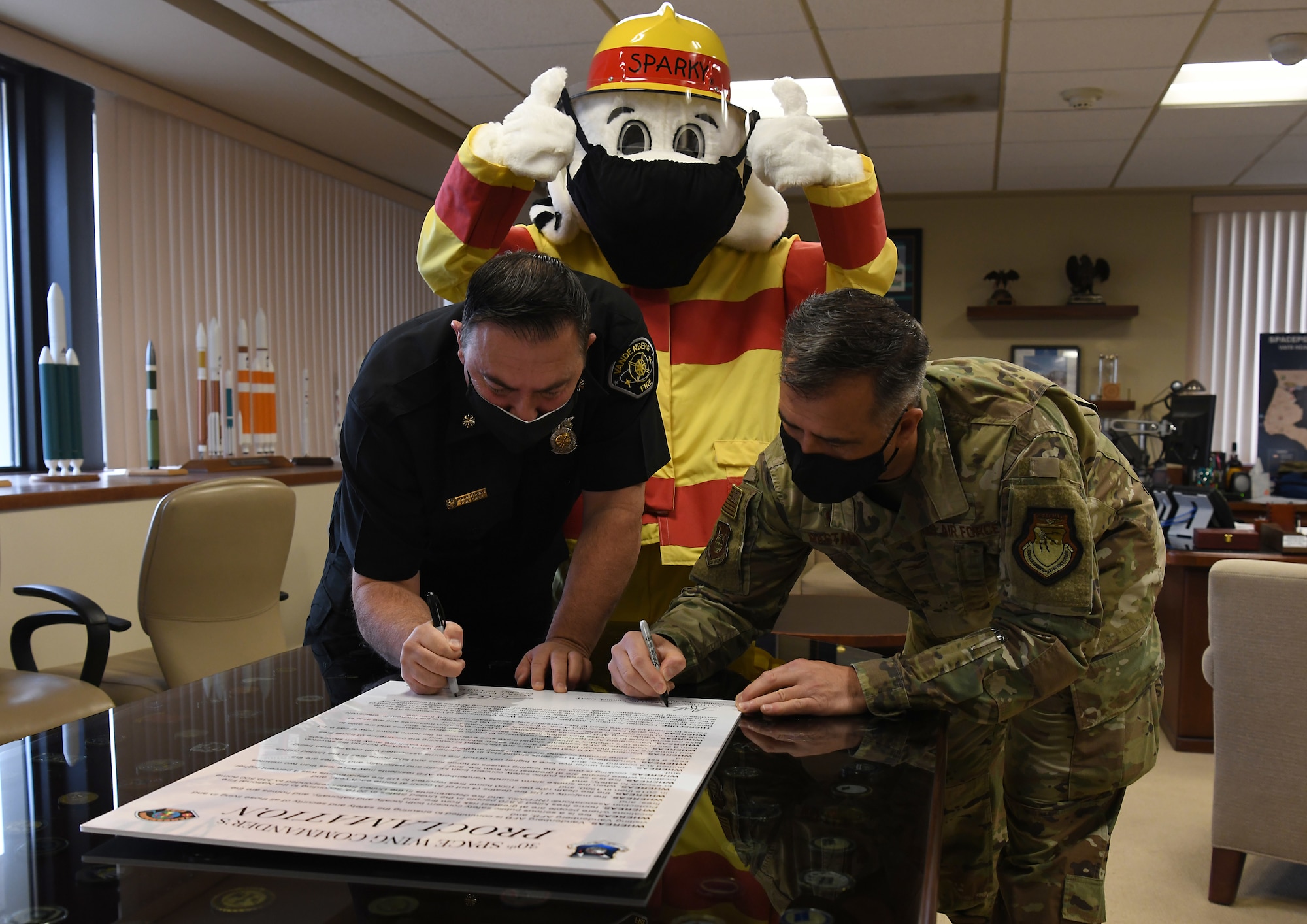 Col. Anthony Mastalir, 30th Space Wing commander, and Mark Farias, 30th Civil Engineer Squadron fire chief, sign the 2020 Fire Proclamation with Sparky the Fire Dog Oct. 5, 2020, at Vandenberg Air Force Base, Calif.