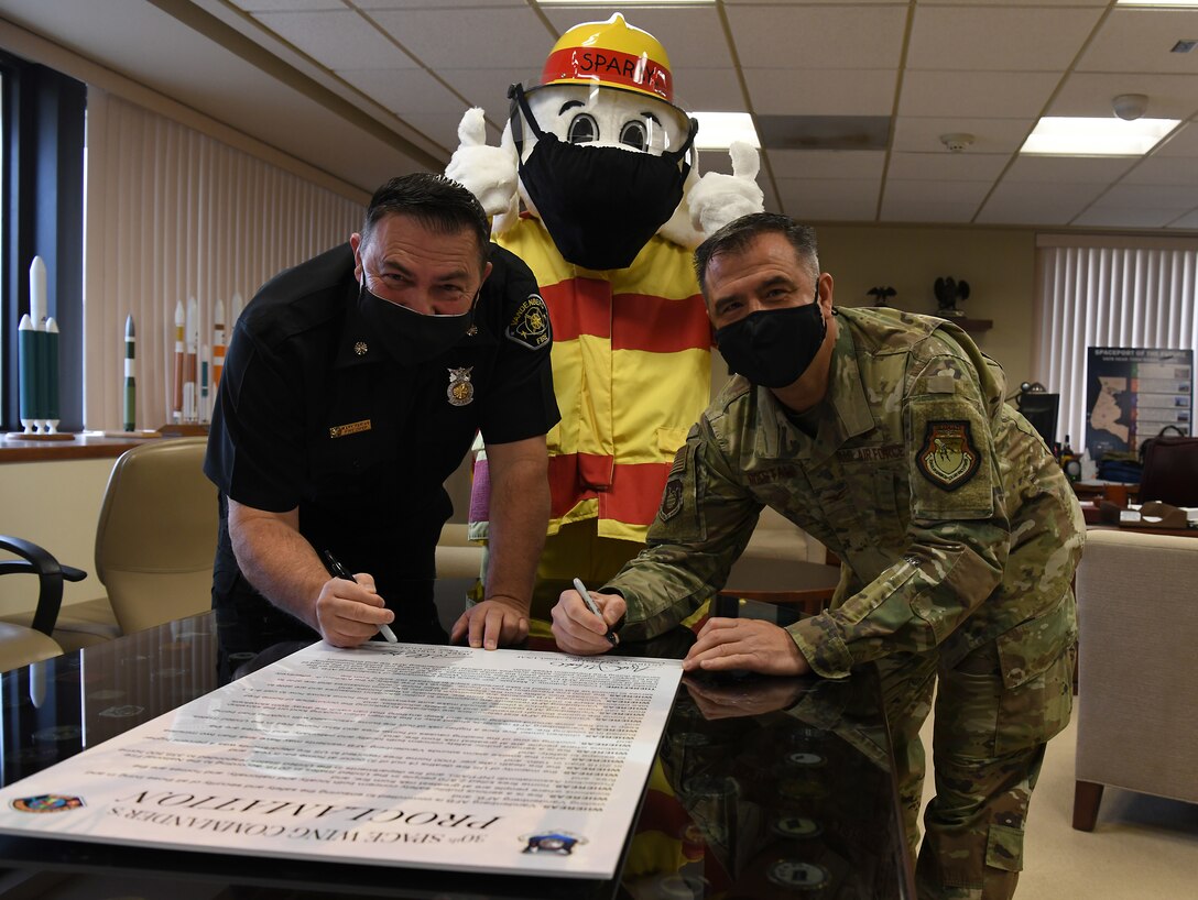 Col. Anthony Mastalir, 30th Space Wing commander, and Mark Farias, 30th Civil Engineer Squadron fire chief, sign the 2020 Fire Proclamation with Sparky the Fire Dog Oct. 5, 2020, at Vandenberg Air Force Base, Calif.