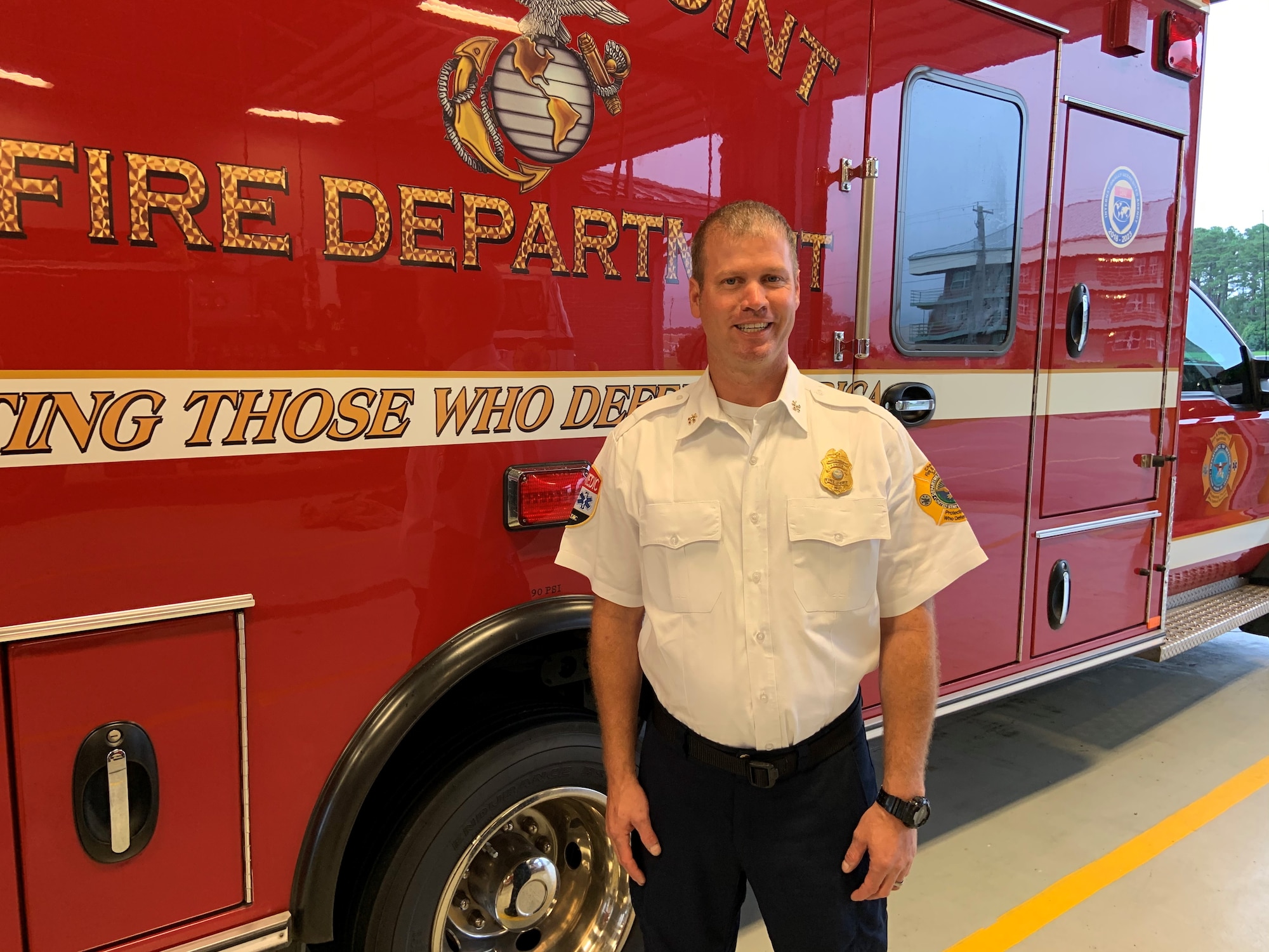 Assistant fire chief stands in front of fire truck