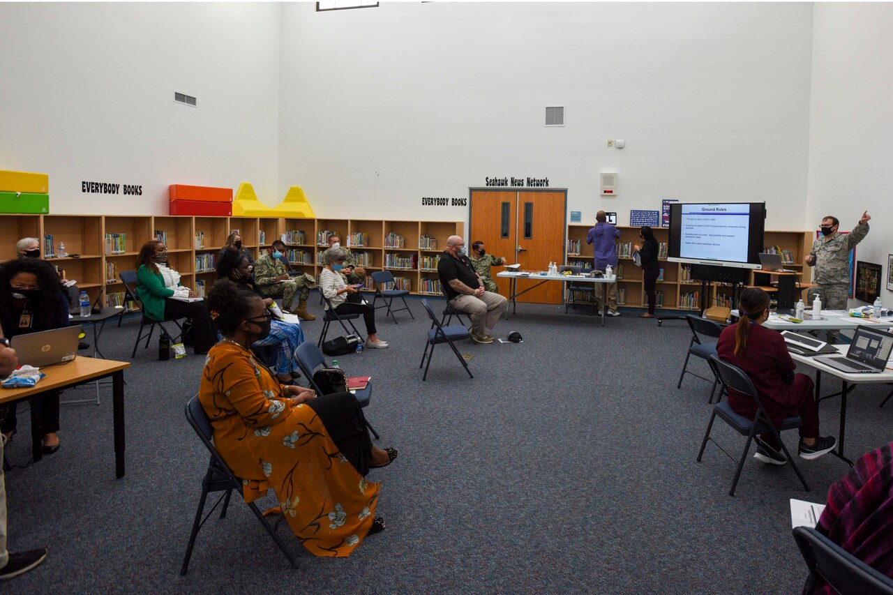 People wearing face masks and following social distancing guidelines participate in a meeting.