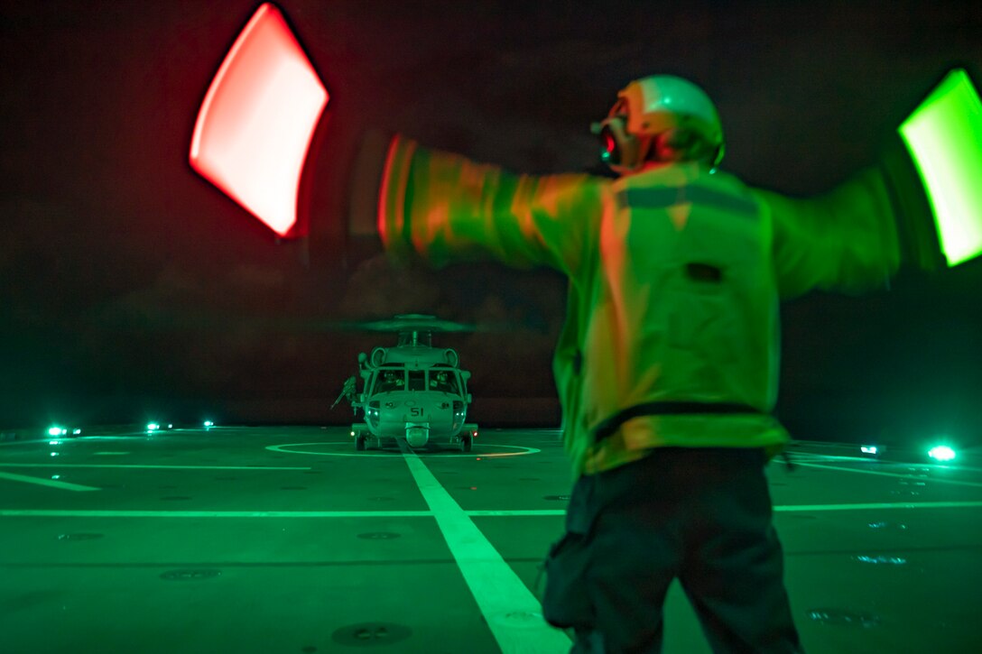 A sailor signals a helicopter.