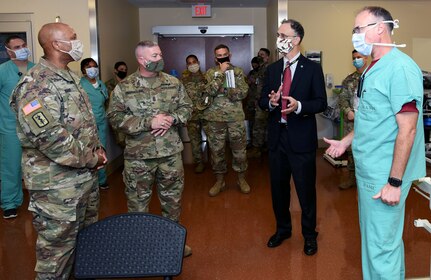 Dr. Leopoldo "Lee" Cancio (center right), director of the U.S. Army Institute of Surgical Research Burn Center and Scott Dewey (right), chief of USAISR Burn Center rehabilitation services explain a burn patient's rehab process to Brig. Gen. Shan K. Bagby, Brooke Army Medical Center commanding general, and BAMC Command Sgt. Maj. Thurman Reynolds.