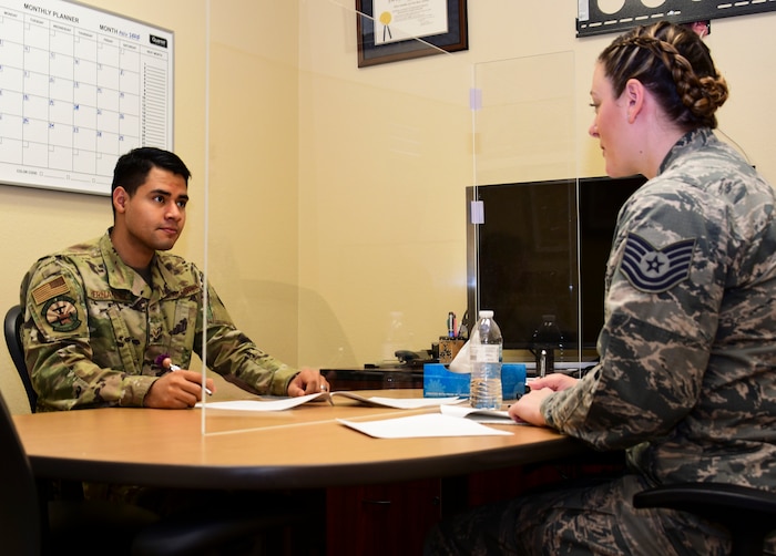 A photo of two Airmen sitting at a table going over information regarding the military complaint process.