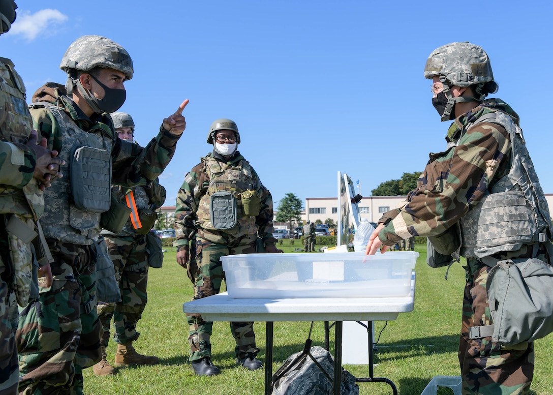 Airmen of the 374th Force Support Squadron demonstrate the correct way to decontaminate during the squadron's war fighting training day.