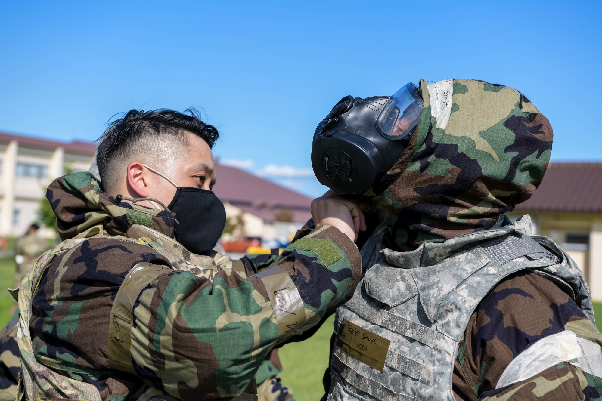 Capt. Jesse Salgado, 374th Force Support Squadron operations officer, left, fastens the hood over the mask for Tech. Sergeant Christopher Smith, 374th Force Support Squadron postmaster during the squadron's war fighting training day.