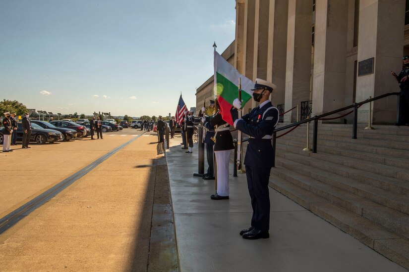 Service members stand outside the Pentagon steps and display the Bulgarian flag.
