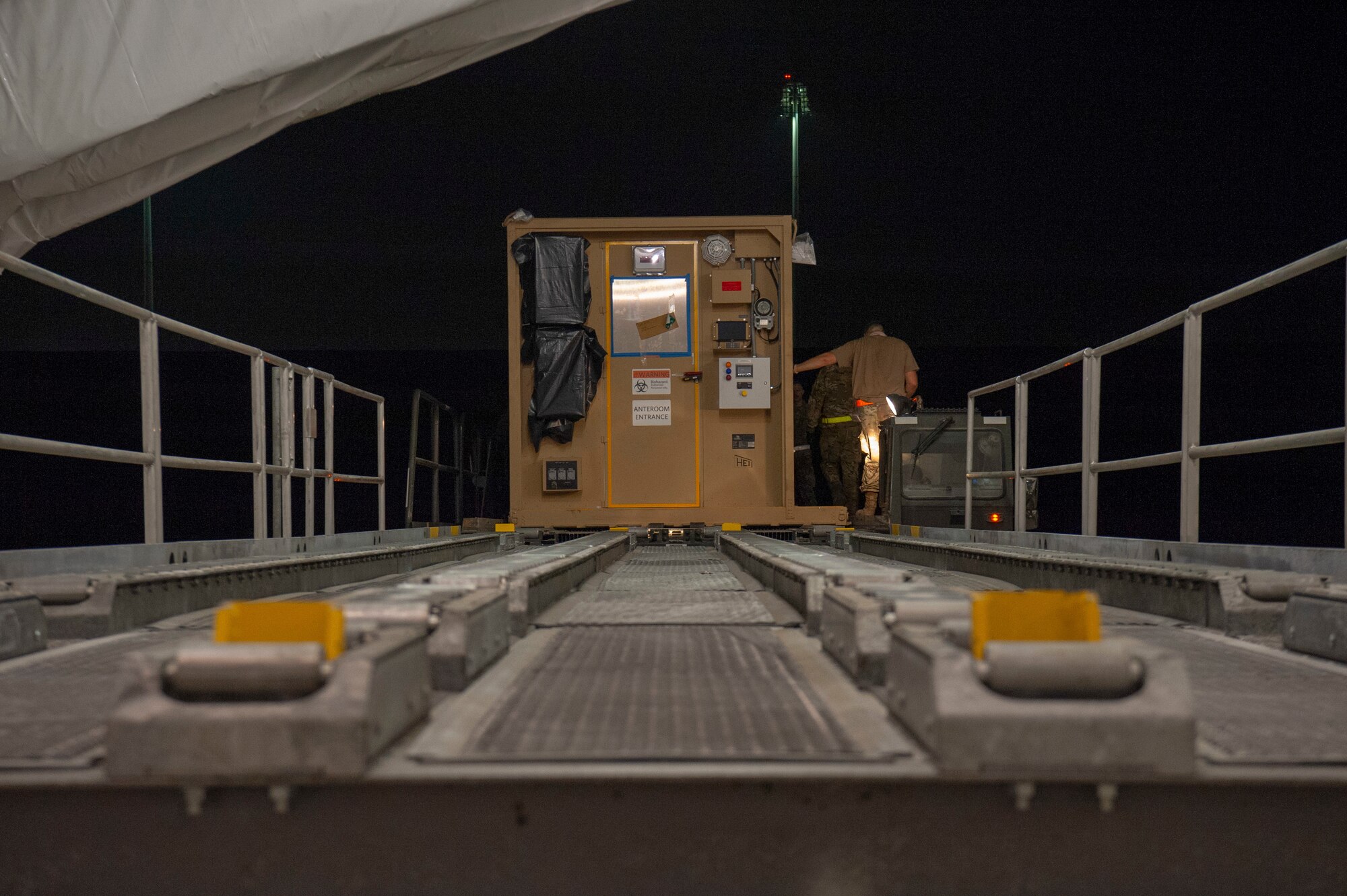 Airmen load a specialized medical container designed to transport individuals with infectious diseases into a clamshell hangar on the flight line of Al Udeid Air Base, Qatar, Sept. 25, 2020. The Negatively Pressurized Conex-Lite, or NPC-L, was received by 379th Expeditionary Aeromedical Evacuation Squadron shortly after the Negatively Pressurized Conex, or NPC. Both medical containers will enable the 379th EAES to safely and expeditiously transport personnel with COVID-19, or other infectious diseases, to higher echelons of care from military installations where isolation or treatment may not be available.