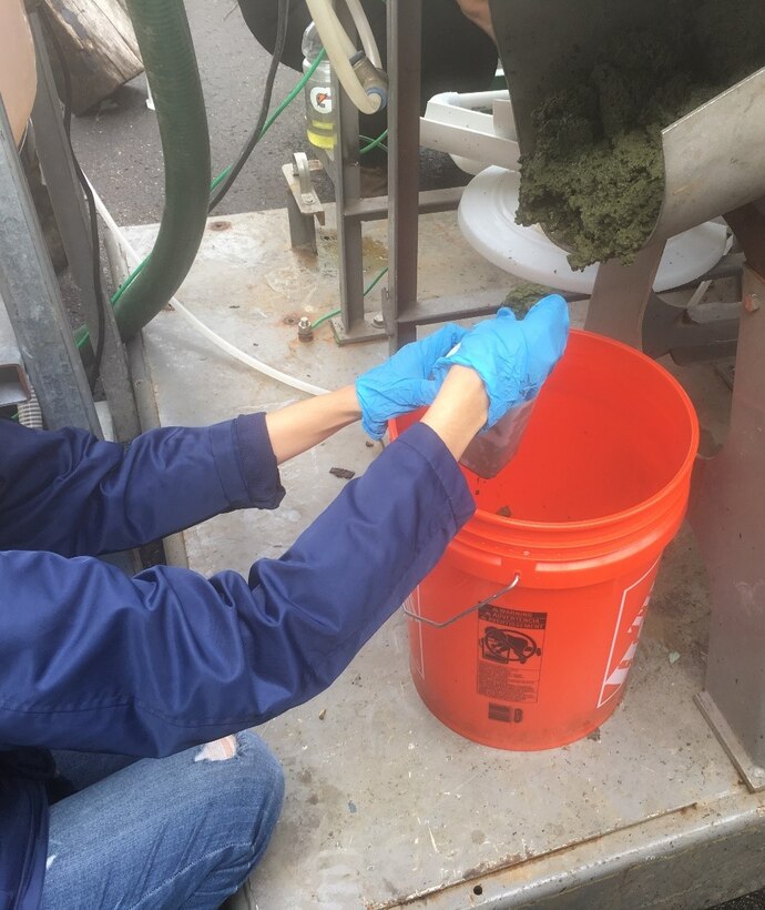 U.S. Army Engineer Research and Development Center (ERDC) researcher Dr. Edith Martinez-Guerra collects concentrated algal biomass samples downstream of the on-site dewatering screw press during validation testing of the on-shore algae harvesting system operated by AECOM. The screw press was a new component of the Harmful Algal Bloom Interception, Treatment, and Transformation System (HABITATS) that improves throughput of the HABITATS process. The demonstration was conducted at Chautauqua Lake, N.Y., Aug. 19 through Sept. 4.