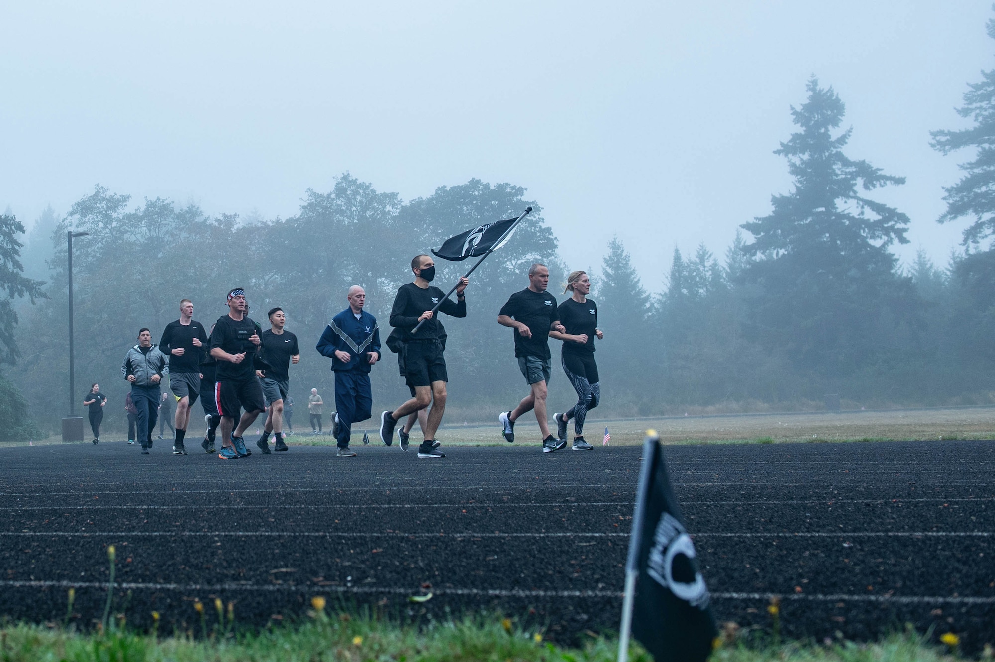 Team McChord Airmen carry a flag during a 24-hour run honoring prisoners of war (POW) and service member missing in action (MIA).