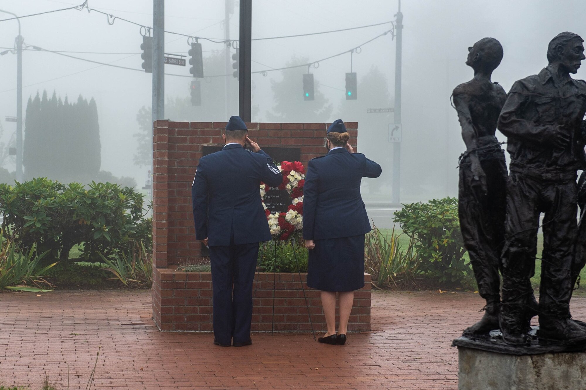 Chief Master Sgt. Joseph Arce, 62nd Airlift Wing command chief, left, and Col. Erin Staine-Pyne, 62nd AW commander, salute during a memorial for prisoners of war (POW) and service members missing in action (MIA).