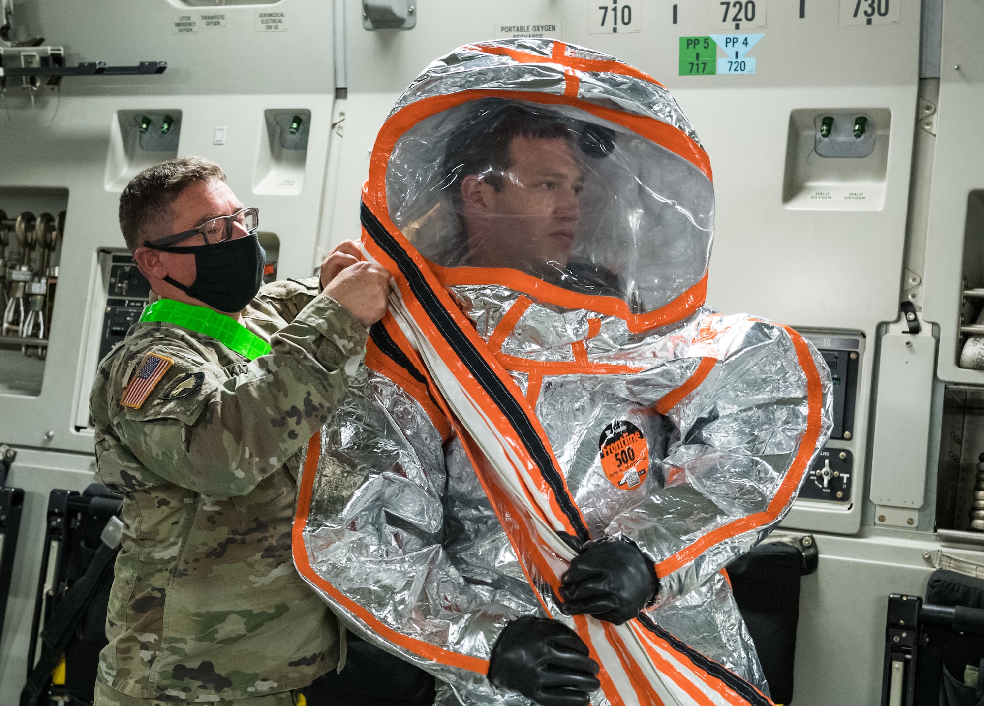 Aboard a C-17 Globemaster III, U.S. Army Chief Warrant Officer 2 Aaron Kazer, 20th Chemical, Biological, Radiological, Nuclear and Explosives Command mobility officer, helps Maj. Mark Quint, 20th CBRNE nuclear disablement team deputy chief, don personal protective equipment for display purposes Sept. 19, 2020, at Dover Air Force Base, Delaware. The 20th CBRNE Command recently conducted a deployment readiness exercise, which consisted of several inspections, aerial troop movements and convoys. The 20th CBRNE Command ensures the effective countering of CBRNE hazards at home and abroad. Dover AFB serves as the primary port of embark for the 20th CBRNE Command during both exercises and operations and regularly supports similar joint missions. (U.S. Air Force photo by Roland Balik)