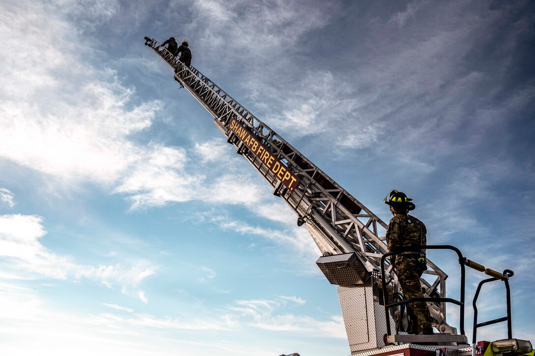 Airmen climb a ladder as another airman watches.