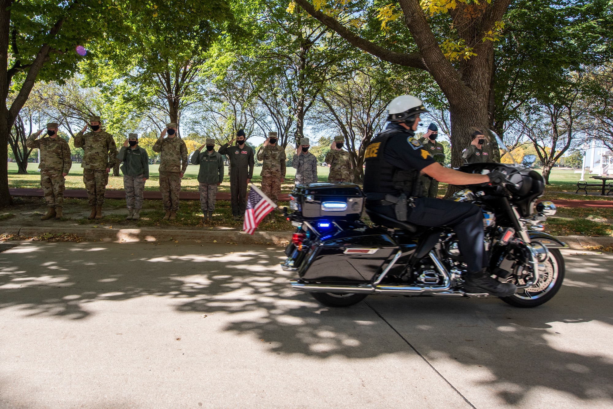 A motorcycle passes a saluting group of Airmen.