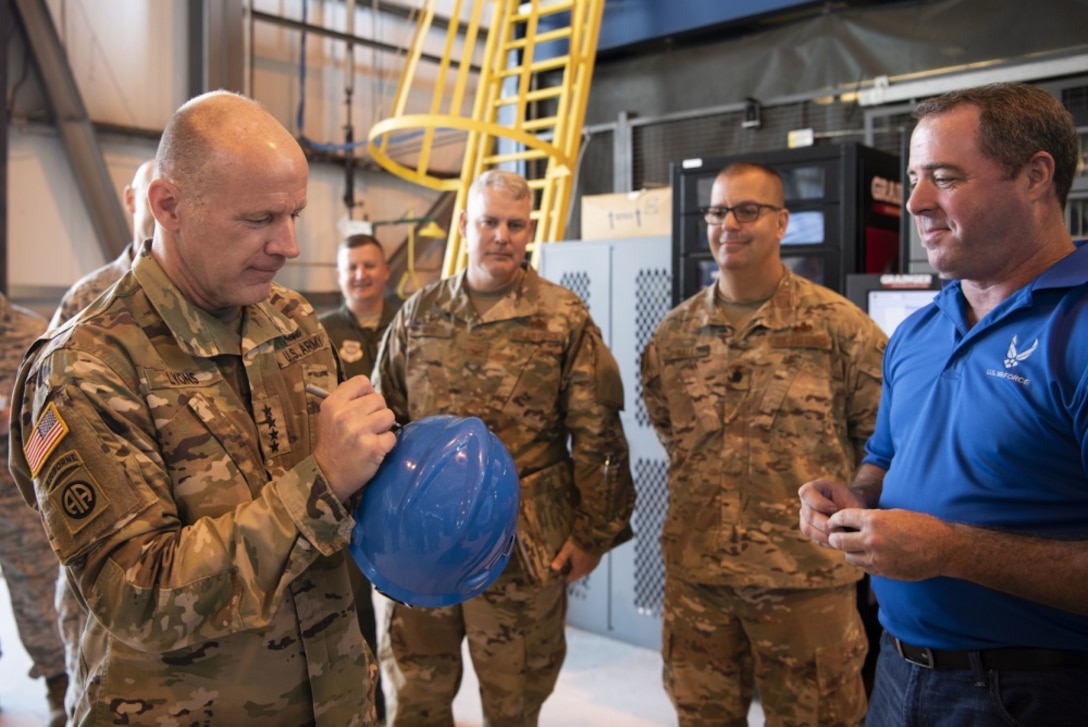 A general officer autographs a hard hat during a visit.