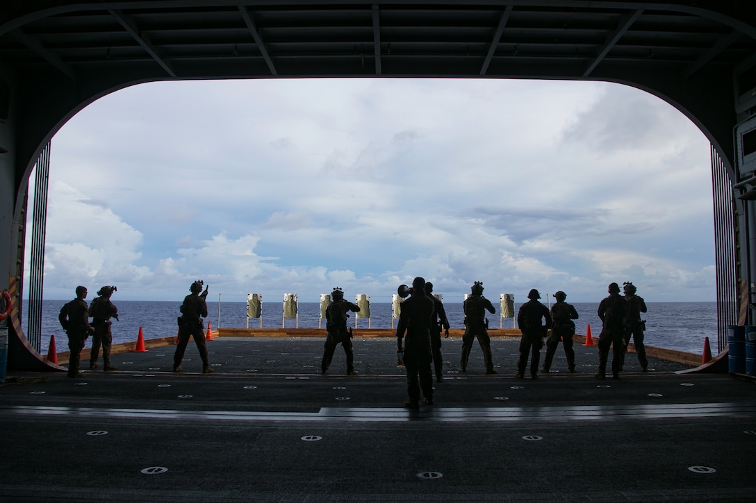 A group of sailors fire at targets on the deck of a ship.