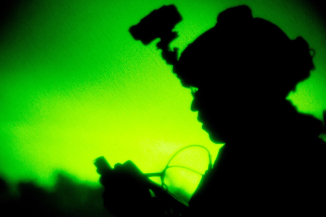 A Marine wearing a helmet is seen in night vision.