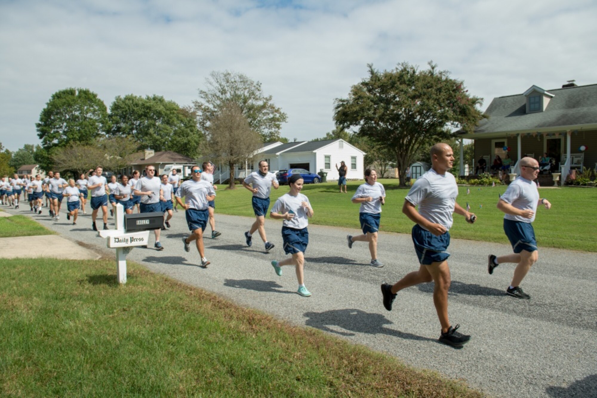 Airmen run in formation past homes in a neighborhood
