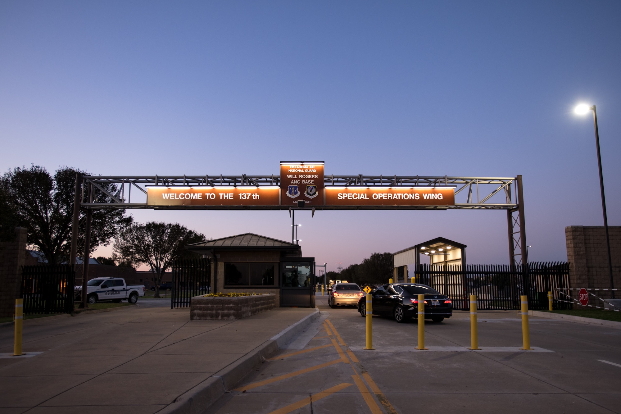 At dawn, Guardsmen enter Will Rogers Air National Guard Base through the updated main gate in Oklahoma City on Oct. 3, 2020. The gate now includes upgraded anti-terrorism force protection measures as well as improved exterior lighting, which was converted to a more energy efficient LED alternative. The new lights use 75% less energy and last 25 times longer than incandescent lighting. Modifications to the main gate were completed on June 19, 2020. (U.S. Air National Guard photo by Senior Airman Alex Kaelke)