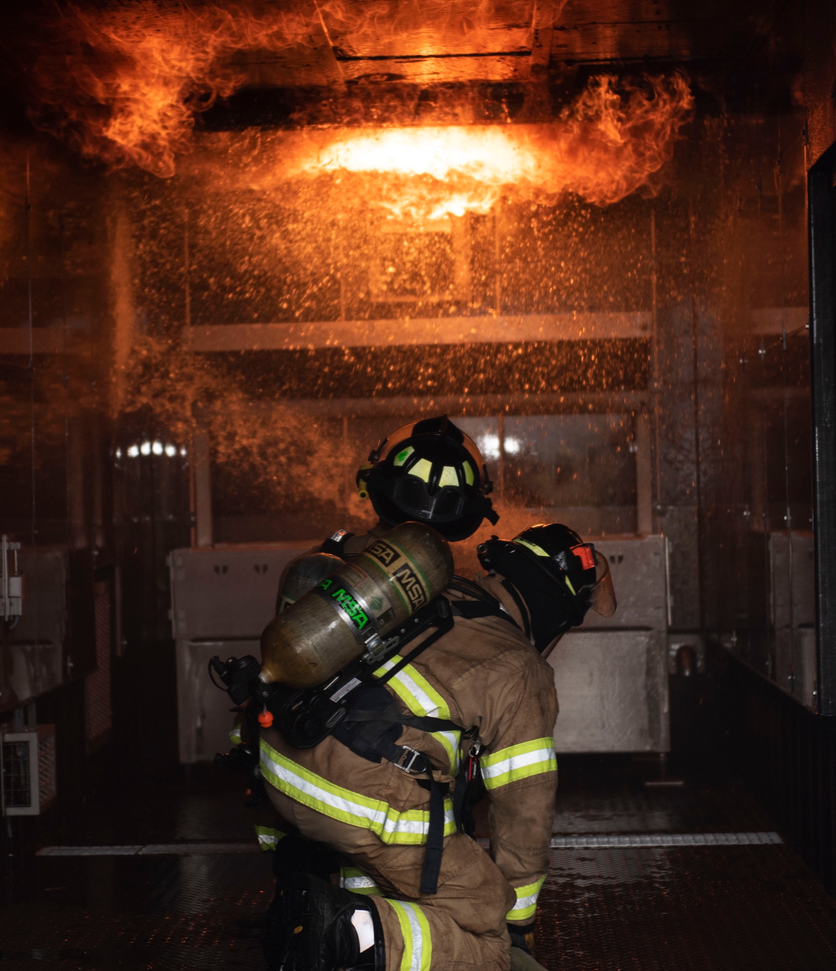 U.S. Air Force Airman 1st Class Andre Korte, left, and A1C Nathaniel Corder, 52nd Civil Engineer Squadron Fire and Emergency Services firefighters, prepare for a building fire simulation, Oct. 5, 2020, at Spangdahlem Air Base, Germany. The Spangdahlem Fire Department demonstrated this simulator to 52nd Fighter Wing leadership during Fire Prevention Week, to showcase their capabilities and mission readiness in case of building fires. (U.S. Air Force photo by Senior Airman Melody W. Howley)