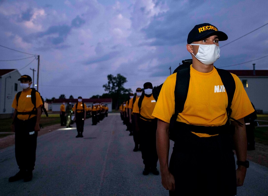 Navy recruits wearing face mask stand in formation.