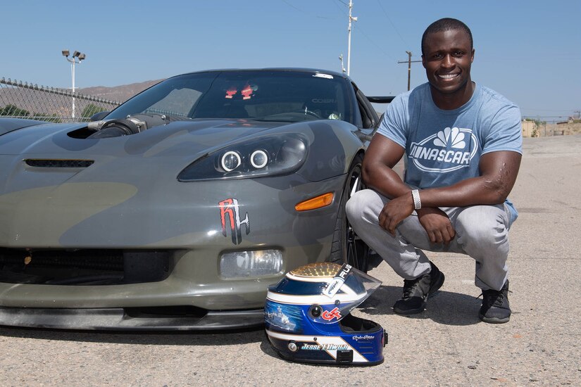 A man crouches next to a car.