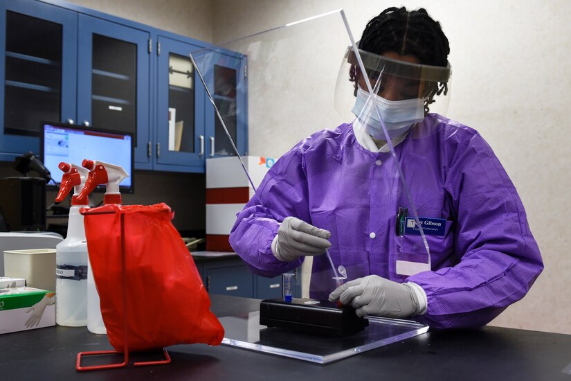 An airman in medical outfit prepares a sample for testing.