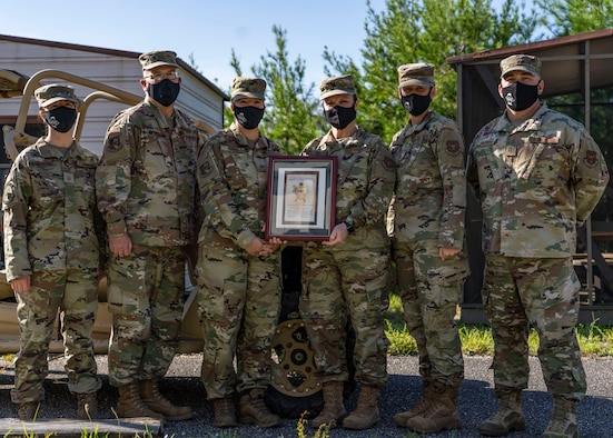 Photo of an Airman handing another Airman and award