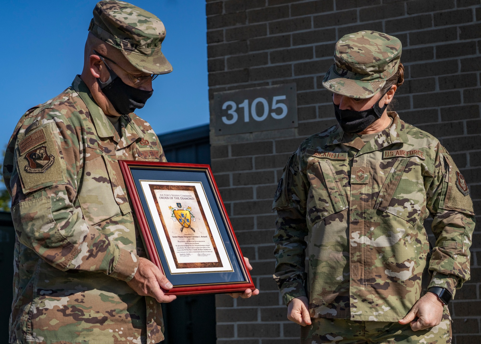 Photo of an Airman handing another Airman and award