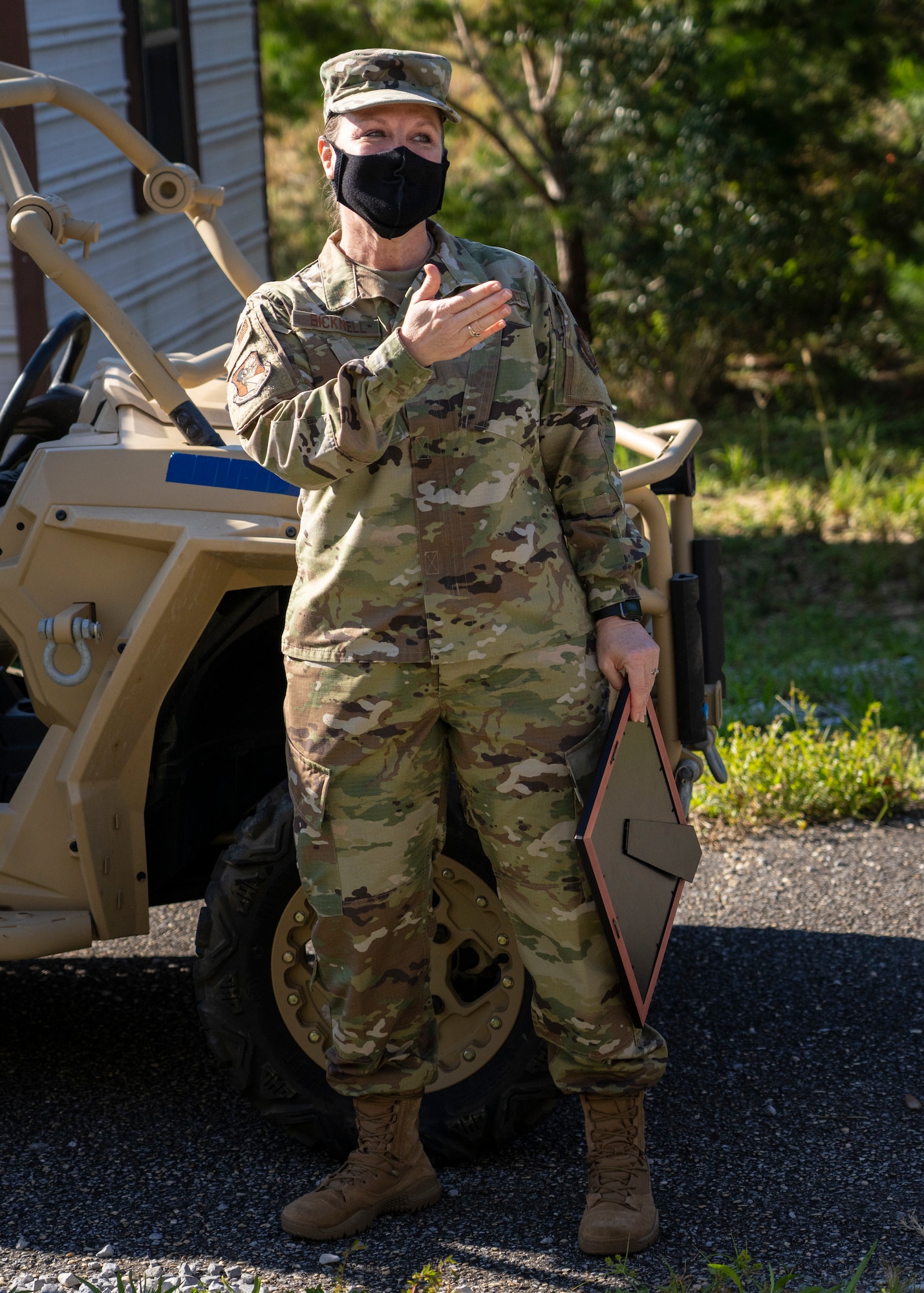 Photo of an Airman standing holding an frame while gesturing