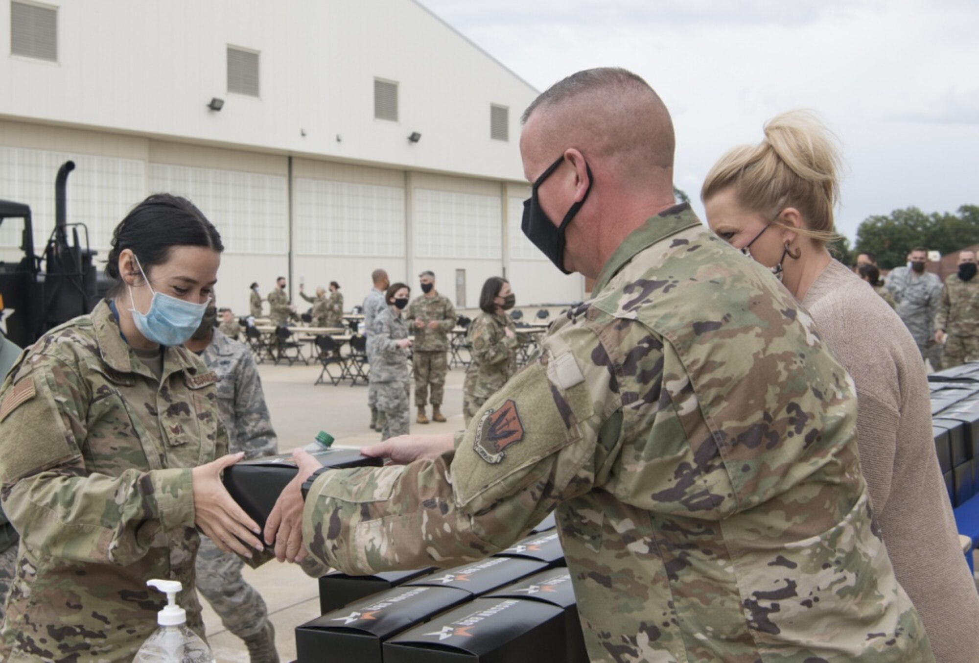 An Airman receives a lunch box from another Airman