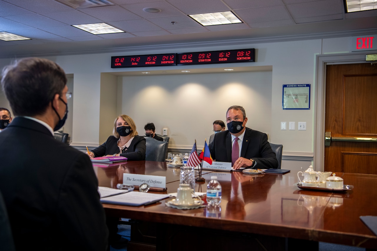 Two men sit at a table across from one another.