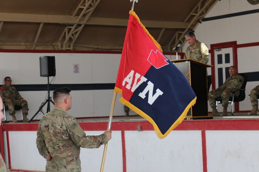 U.S. Army Pfc. Zachary Snyder, human resources specialist with Headquarters and Headquarters Company, 28th Expeditionary Combat Aviation Brigade holds the brigade colors during a transfer of authority ceremony.