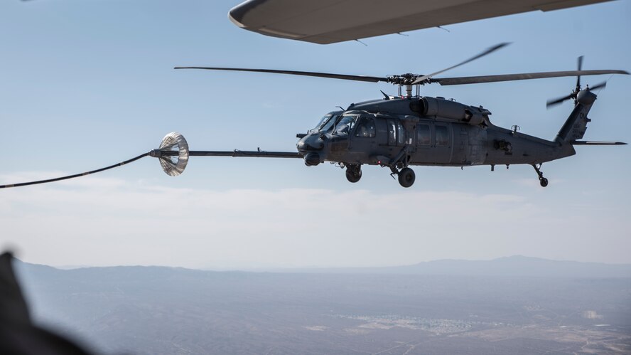 A photo of a helicopter performing air-to-air refueling